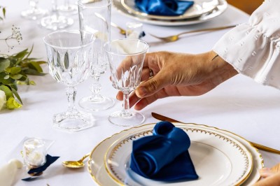 Tente blanche montée sur une pelouse, entourée de personnes et de tables, dans une cour avec bâtiments en arrière-plan.