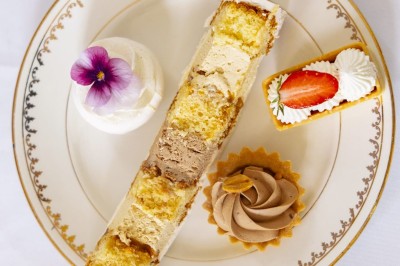 Tente blanche montée sur une pelouse, entourée de personnes et de tables, dans une cour avec bâtiments en arrière-plan.