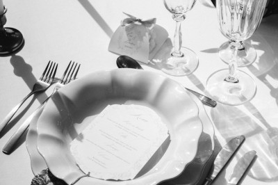 Tente blanche montée sur une pelouse, entourée de personnes et de tables, dans une cour avec bâtiments en arrière-plan.