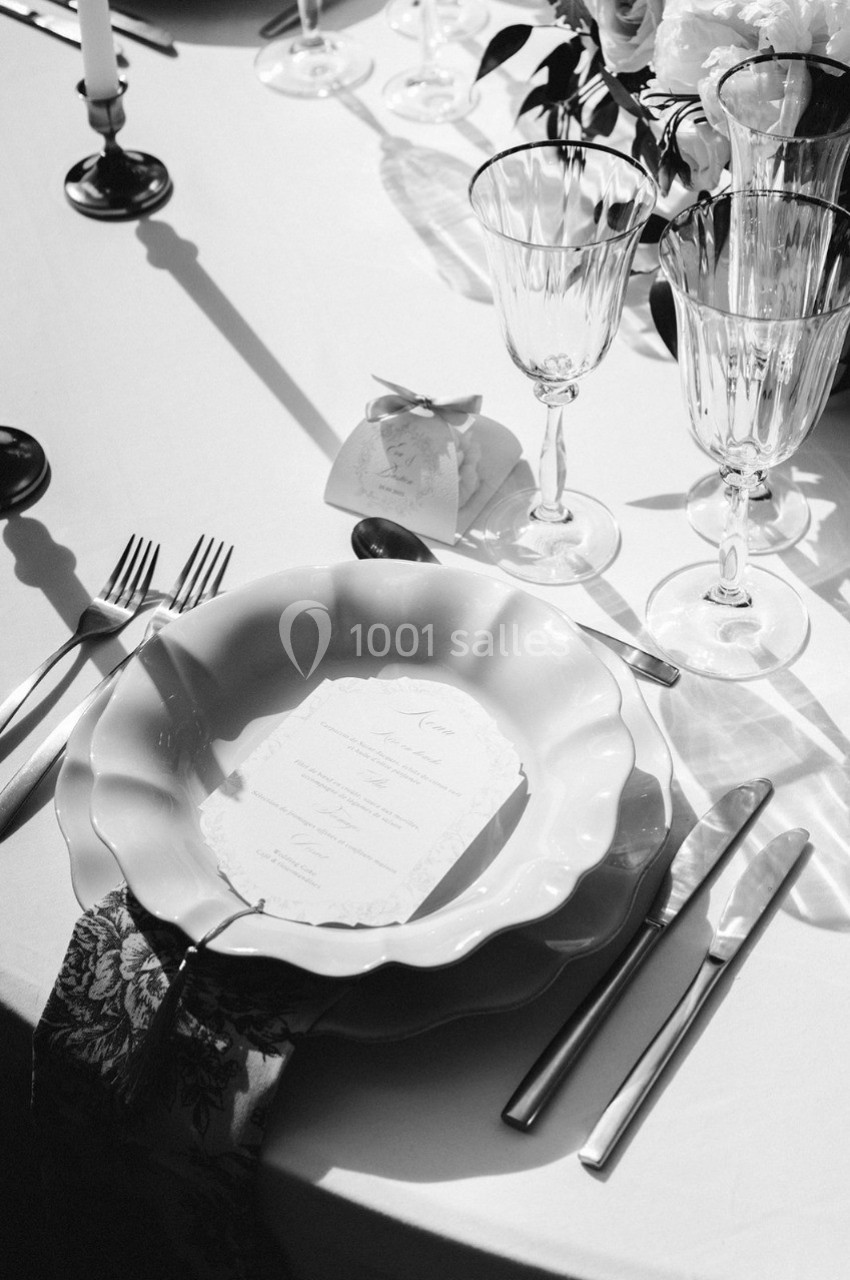 Table dressée avec assiette, couverts, verres en cristal, menu et décoration élégante en noir et blanc.