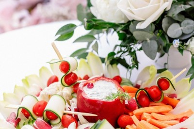 Tente blanche montée sur une pelouse, entourée de personnes et de tables, dans une cour avec bâtiments en arrière-plan.