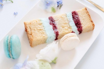 Tente blanche montée sur une pelouse, entourée de personnes et de tables, dans une cour avec bâtiments en arrière-plan.