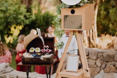 Appareil photo sur trépied en bois avec lampe circulaire, installé dans un jardin verdoyant.