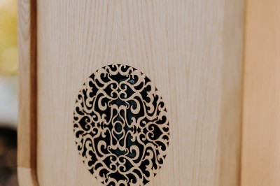 Appareil photo en bois monté sur un trépied, installé dans un jardin avec des arbres en arrière-plan.