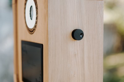 Boîtier en bois sur trépied avec un écran et un objectif circulaire, utilisé en extérieur.