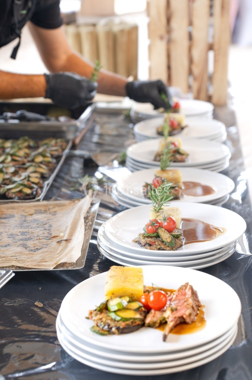 Assiette de viande grillée accompagnée de légumes, sauce et décoration de romarin, servie sur une table de présentation.
