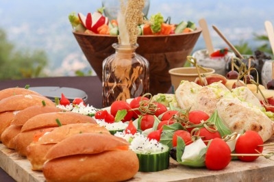 Plateau de buffet avec pains garnis, légumes frais, tomates cerises, fromage et desserts en arrière-plan.