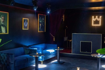 Enseigne néon rouge ’Pigalle Mon Amour’ sur un mur sombre encadrée par des rideaux rouges.