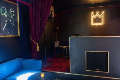 Enseigne néon rouge ’Pigalle Mon Amour’ sur un mur sombre encadrée par des rideaux rouges.