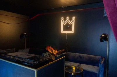 Enseigne néon rouge ’Pigalle Mon Amour’ sur un mur sombre encadrée par des rideaux rouges.