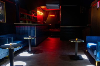 Enseigne néon rouge ’Pigalle Mon Amour’ sur un mur sombre encadrée par des rideaux rouges.