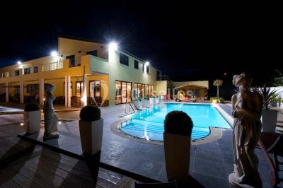 Piscine extérieure entourée de terrasses en bois et de chaises longues, devant une maison moderne sous un ciel dégagé.