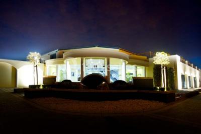 Piscine extérieure entourée de terrasses en bois et de chaises longues, devant une maison moderne sous un ciel dégagé.