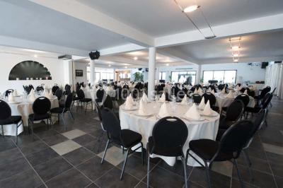 Piscine extérieure entourée de terrasses en bois et de chaises longues, devant une maison moderne sous un ciel dégagé.