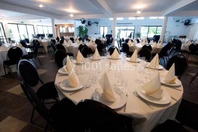 Piscine extérieure entourée de terrasses en bois et de chaises longues, devant une maison moderne sous un ciel dégagé.
