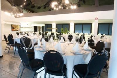 Piscine extérieure entourée de terrasses en bois et de chaises longues, devant une maison moderne sous un ciel dégagé.