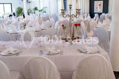 Piscine extérieure entourée de terrasses en bois et de chaises longues, devant une maison moderne sous un ciel dégagé.