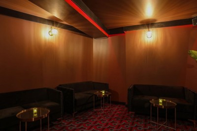 Façade d'un établissement avec une entrée vitrée, éclairée par une lumière rouge et une enseigne lumineuse bleue.