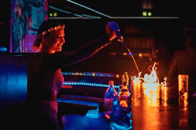 Miniature Cocktail Club Un chanteur interprète sur scène, micro à la bouche, éclairé par une lumière chaude, avec un public en arrière-plan.