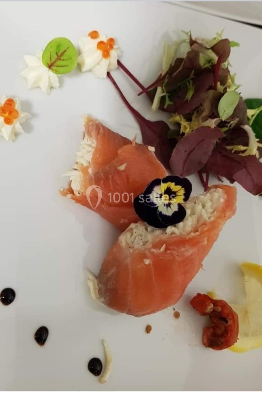 Assiette composée de saumon fumé farci, salade verte, citron, crevette, fleurs comestibles et décorations culinaires.