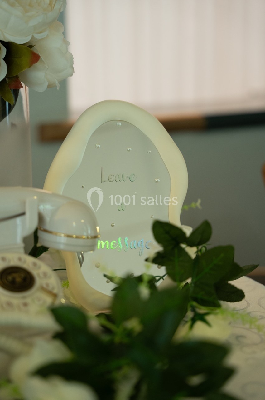 Plaque décorative avec l'inscription ’Leave a message’ entourée de fleurs et d'un téléphone rétro.