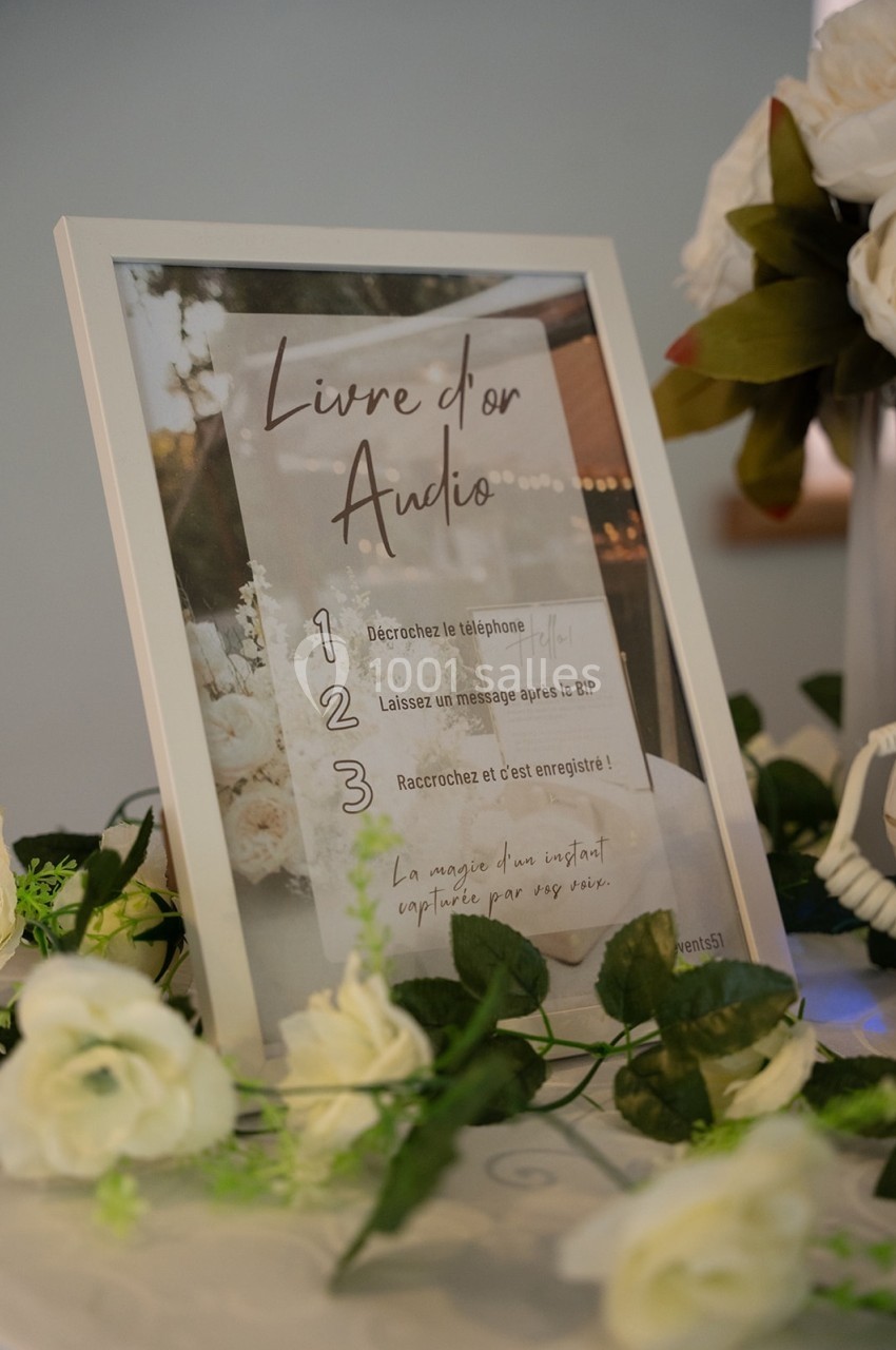 Cadre contenant les instructions d'utilisation d'un livre d'or audio, entouré de fleurs blanches décoratives.
