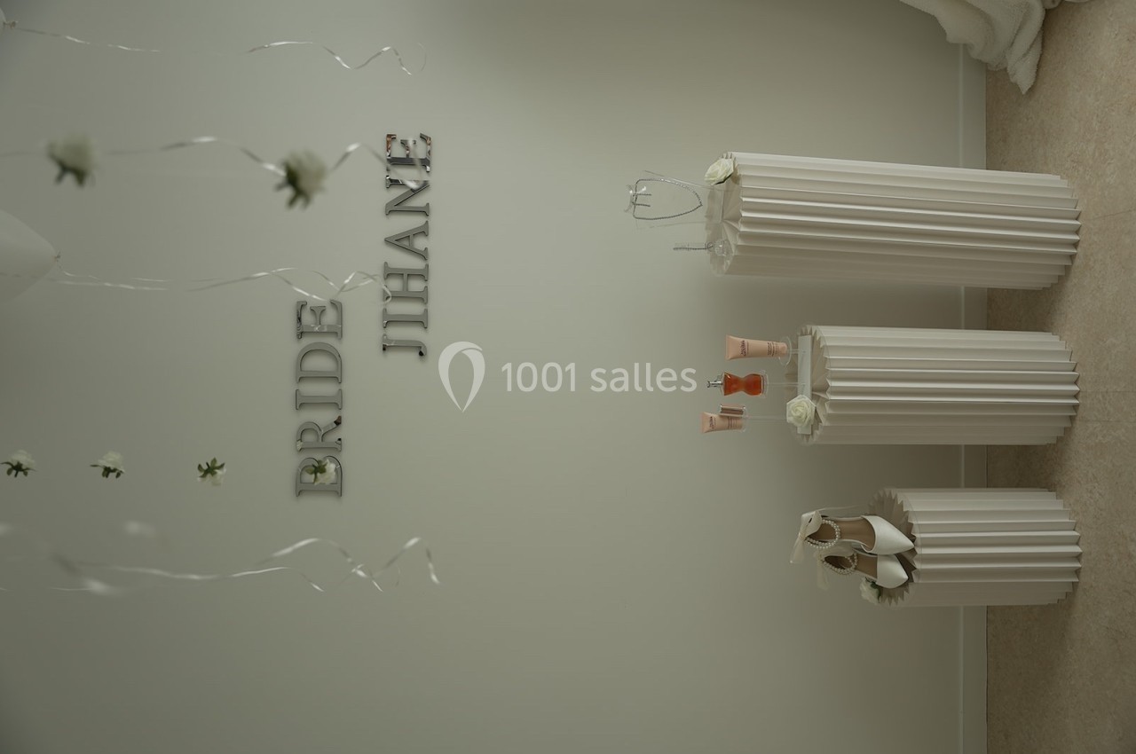 Décoration minimaliste avec colonnes blanches, accessoires de mariage et ballons suspendus dans une pièce lumineuse.