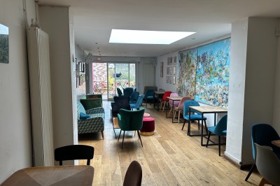 Terrasse extérieure avec tables et chaises colorées, entourée de murs en briques et végétation.