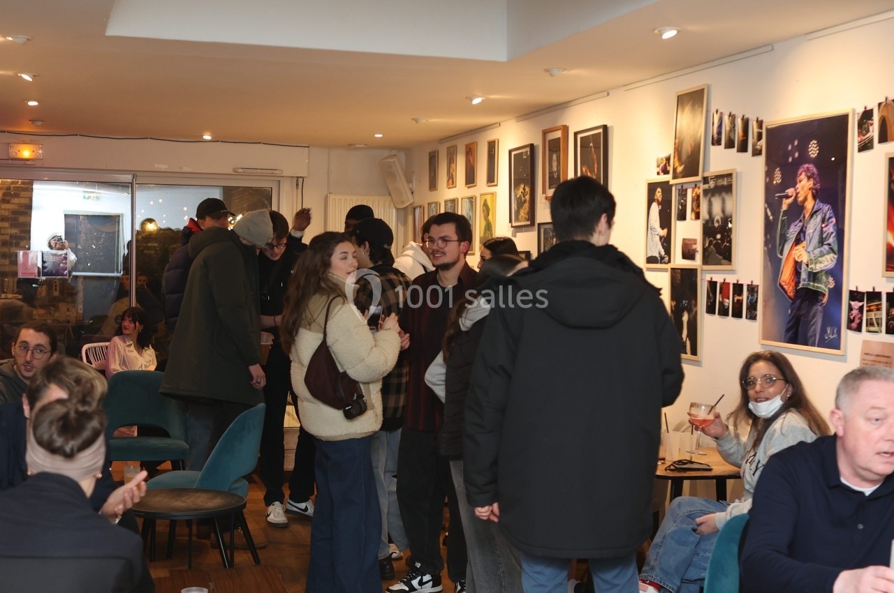 Des personnes discutent et se détendent dans un espace intérieur décoré de photos et affiches artistiques.