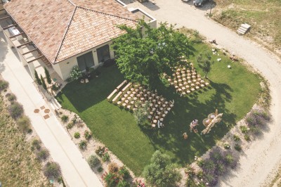 Bâtiment moderne éclairé en soirée, entouré d'arbres et d'un jardin sombre sous un ciel crépusculaire.