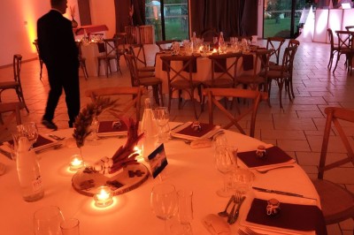 Bâtiment moderne éclairé en soirée, entouré d'arbres et d'un jardin sombre sous un ciel crépusculaire.