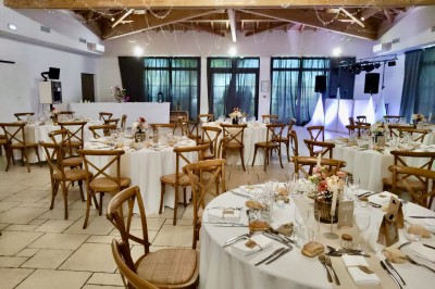 Bâtiment moderne éclairé en soirée, entouré d'arbres et d'un jardin sombre sous un ciel crépusculaire.