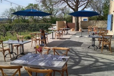 Bâtiment moderne éclairé en soirée, entouré d'arbres et d'un jardin sombre sous un ciel crépusculaire.