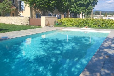 Bâtiment moderne éclairé en soirée, entouré d'arbres et d'un jardin sombre sous un ciel crépusculaire.