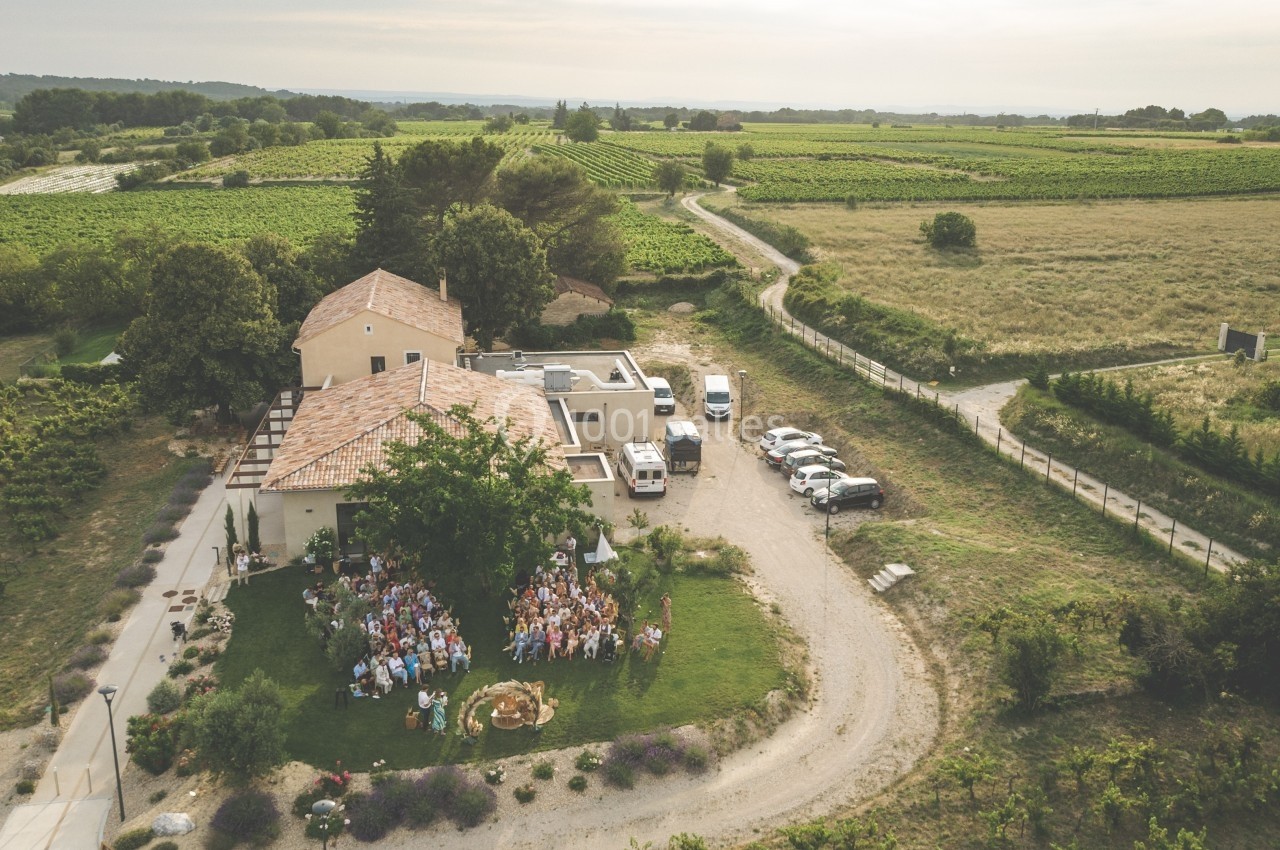 Vue aérienne d'une réunion en plein air devant un bâtiment entouré de champs et de vignes.