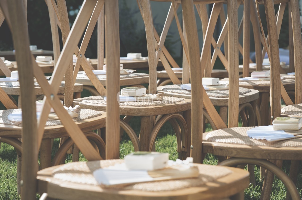 Chaises en bois disposées en rangées sur une pelouse, avec des coussins et des livrets posés sur les assises.
