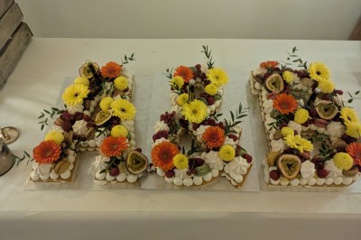 Assiette avec un morceau de viande nappé de sauce, purée, garniture de légumes et fleur comestible en décoration.
