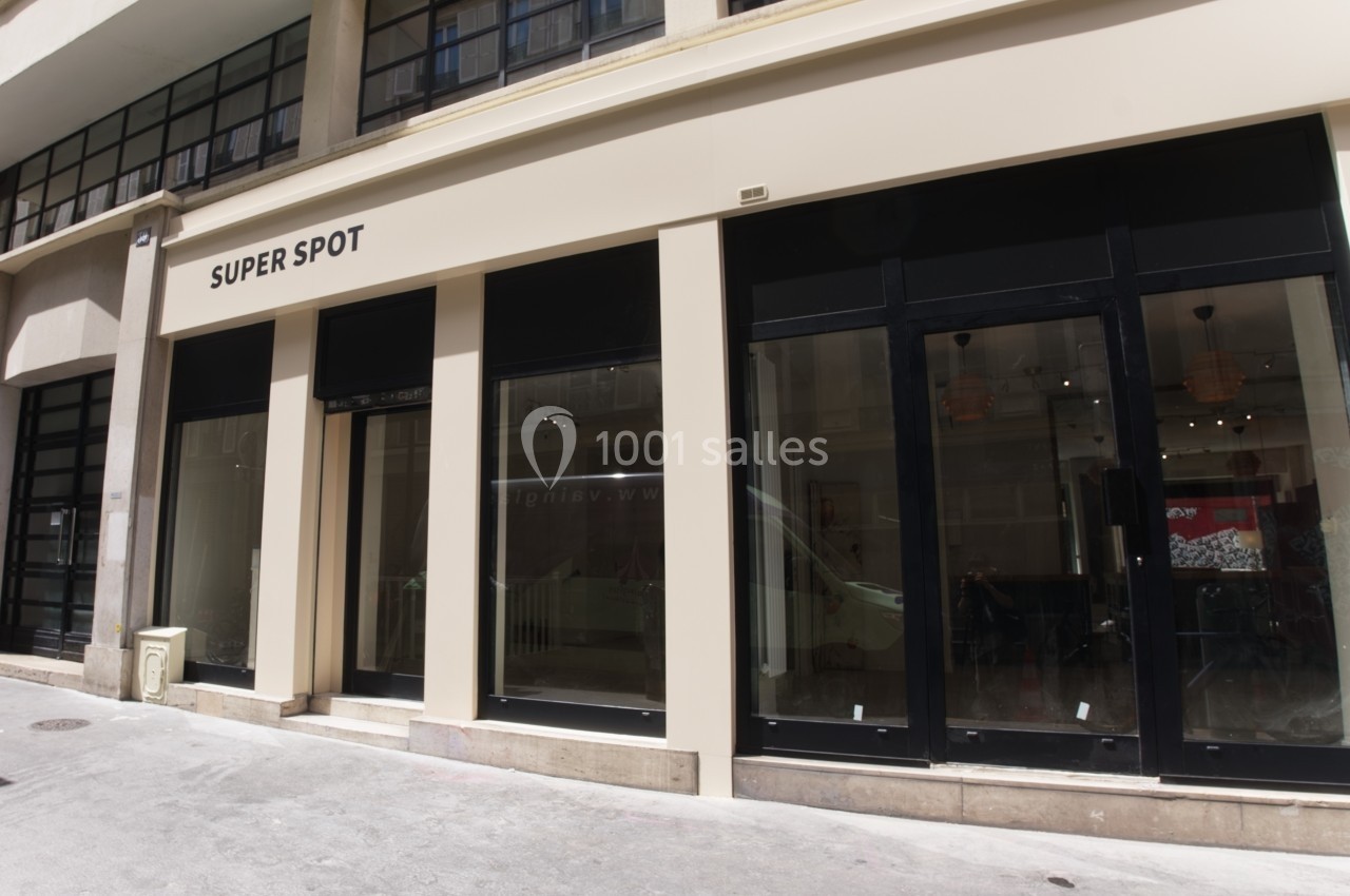 Façade d'un bâtiment moderne avec de grandes vitrines et une enseigne ’Super Spot’ visible au-dessus de l'entrée.