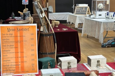 Des personnes tiennent un parachute coloré avec des trous, utilisé pour une activité de groupe en extérieur sur une pelouse.