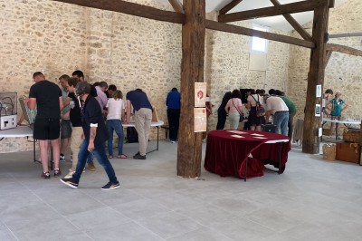 Des personnes tiennent un parachute coloré avec des trous, utilisé pour une activité de groupe en extérieur sur une pelouse.