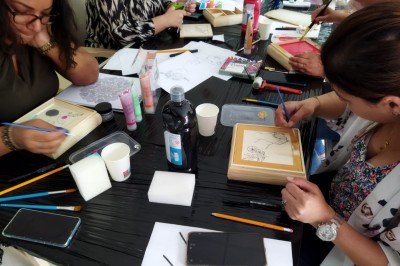Des personnes tiennent un parachute coloré avec des trous, utilisé pour une activité de groupe en extérieur sur une pelouse.