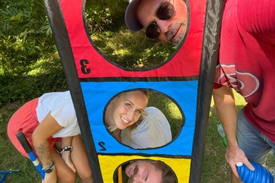 Des personnes tiennent un parachute coloré avec des trous, utilisé pour une activité de groupe en extérieur sur une pelouse.