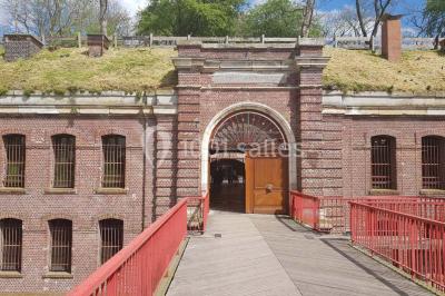 Espace extérieur aménagé pour un événement avec tables hautes, buffet et tente blanche, entouré de verdure.