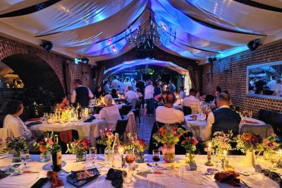 Espace extérieur aménagé pour un événement avec tables hautes, buffet et tente blanche, entouré de verdure.