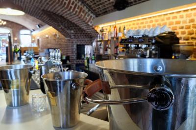 Espace extérieur aménagé pour un événement avec tables hautes, buffet et tente blanche, entouré de verdure.