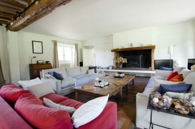 Paysage verdoyant avec arbres feuillus, pelouse ensoleillée et petit pont en pierre près d'un ruisseau.