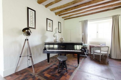 Paysage verdoyant avec arbres feuillus, pelouse ensoleillée et petit pont en pierre près d'un ruisseau.