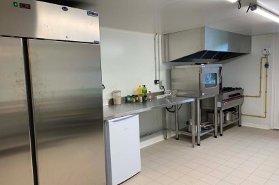 Chambre avec un lit double, murs verts, grande fenêtre donnant sur un paysage champêtre et éclairage doux.