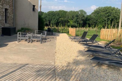 Chambre avec un lit double, murs verts, grande fenêtre donnant sur un paysage champêtre et éclairage doux.