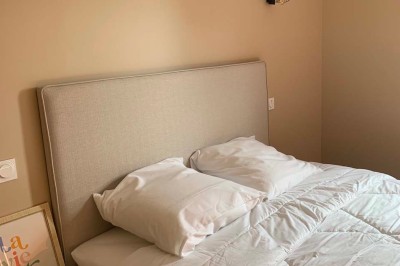 Chambre avec un lit double, murs verts, grande fenêtre donnant sur un paysage champêtre et éclairage doux.